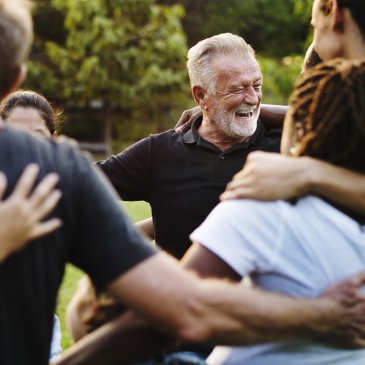 Group of people in a circle featuring a senior man laughing