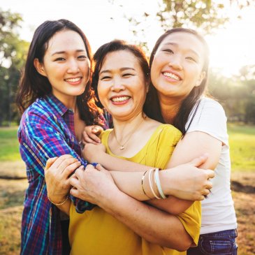 Two smiling teenage daughters hug their mom