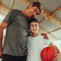Man hugging boy on basketball court